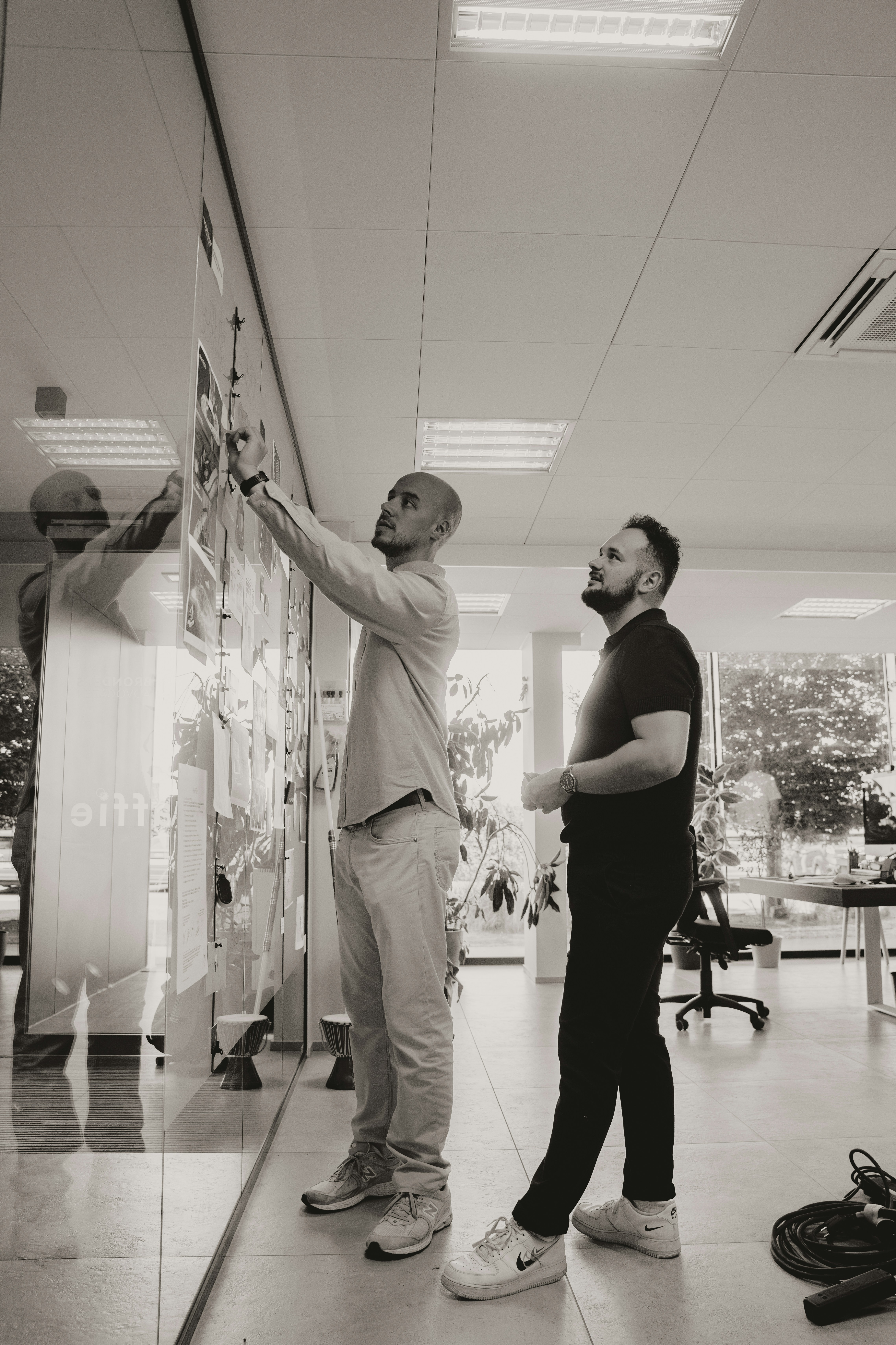 Two colleagues reviewing project boards on an office wall